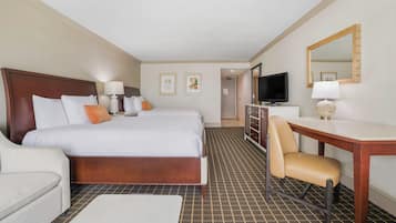 A hotel room with a large bed, a desk, a chair, a television, and a mirror.