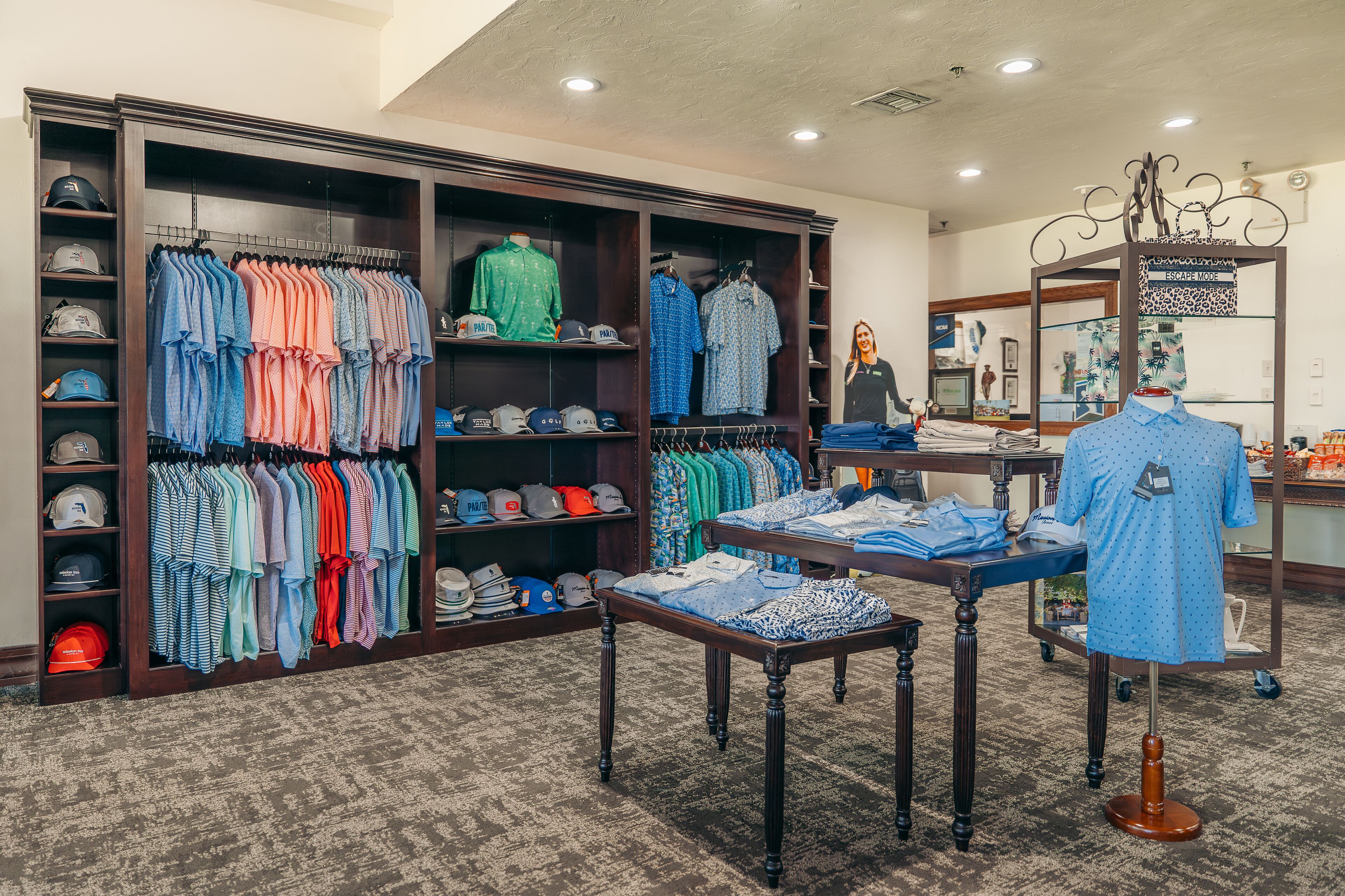 Una tienda de ropa con perchas llenas de camisas y un maniquí mostrando una camisa azul.