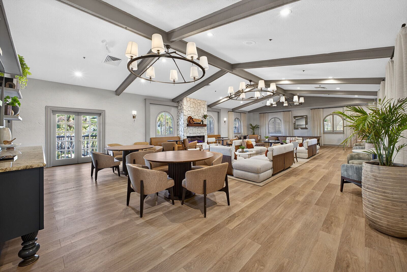 A spacious living room with a fireplace, wooden flooring, and a large dining area with round tables and chairs.