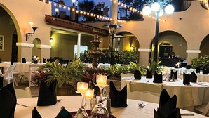 An outdoor dining area with tables set for a meal, surrounded by arches and potted plants. - Mission Resort and Club (Howey-in-the-Hills)