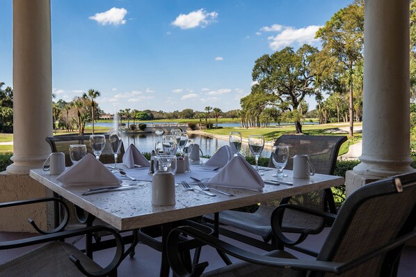 A table set for dining with a view of a water body and trees.
