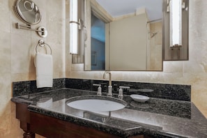 A bathroom with a marble sink, a mirror, and a towel rack.