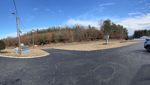 A parking lot with a blue building, a white car, and a tree. - The Inn of Dayville (Dayville)