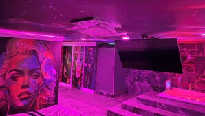 A room with a large mural, a flat-screen TV, and a ceiling with a starry design. - The Inn of Dayville (Dayville)