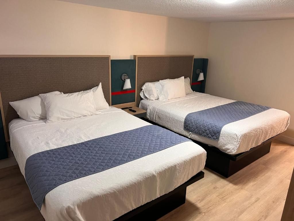 Une chambre d’hôtel avec deux lits, chacun doté d’une tête de lit, de tables de chevet et de lampes.