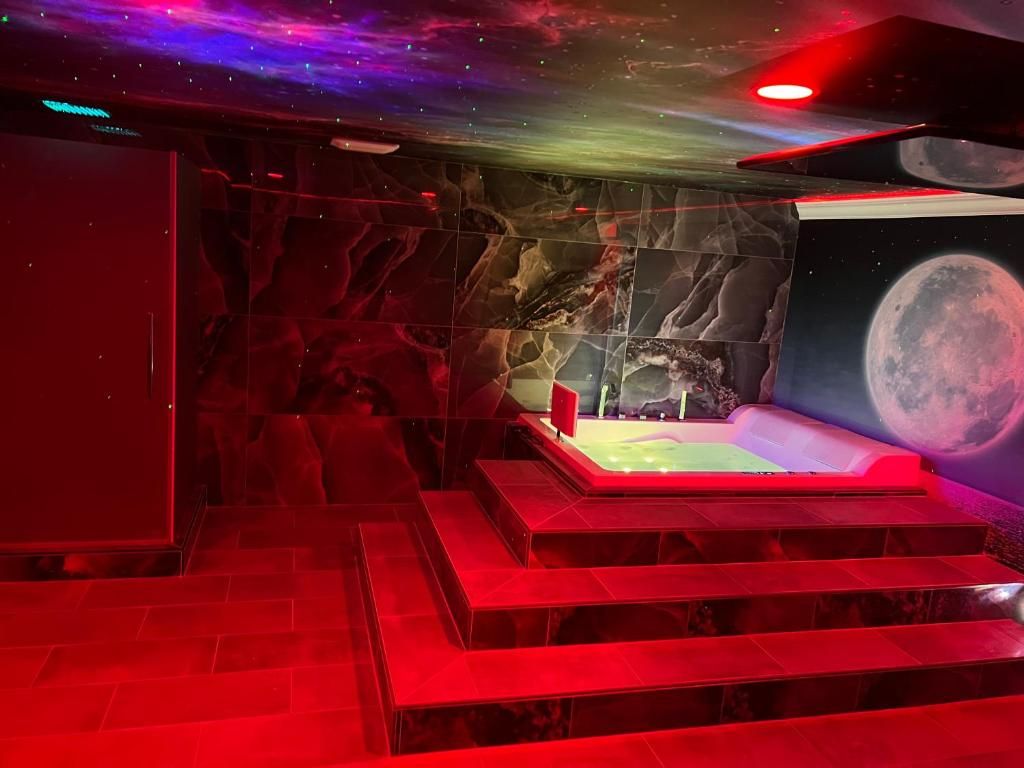 A room with a large space-themed mural, a hot tub, and a staircase.