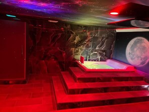 A room with a large space-themed mural, a hot tub, and a staircase. - The Inn of Dayville (Dayville)