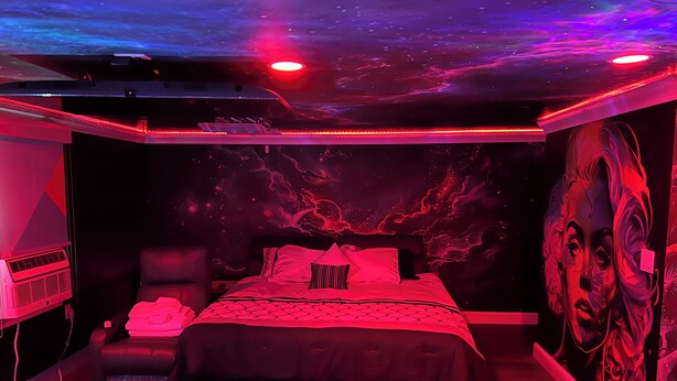 A bedroom with a bed, a couch, and a wall mural. - The Inn of Dayville (Dayville)