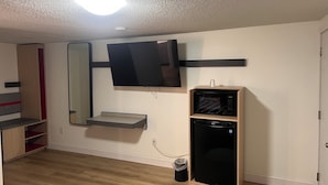 A room with a mounted TV, a microwave, and a small shelf. - The Inn of Dayville (Dayville)