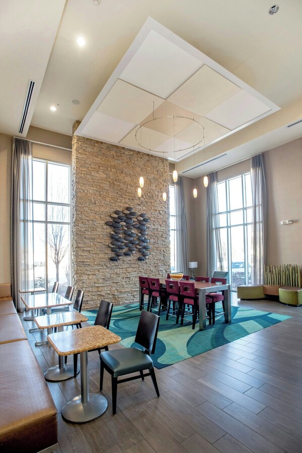 A modern dining area with a stone accent wall, multiple seating options, and large windows providing natural light.