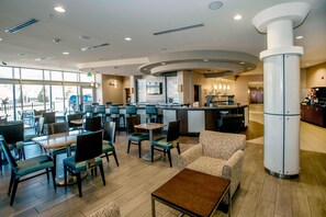 A modern hotel lobby with a central bar area, seating arrangements, and a large pillar. - SpringHill Suites Pueblo Downtown (Pueblo)