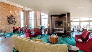 A spacious lobby with a large seating area, a fireplace, and a view of the outdoors through large windows. - SpringHill Suites Pueblo Downtown (Pueblo)