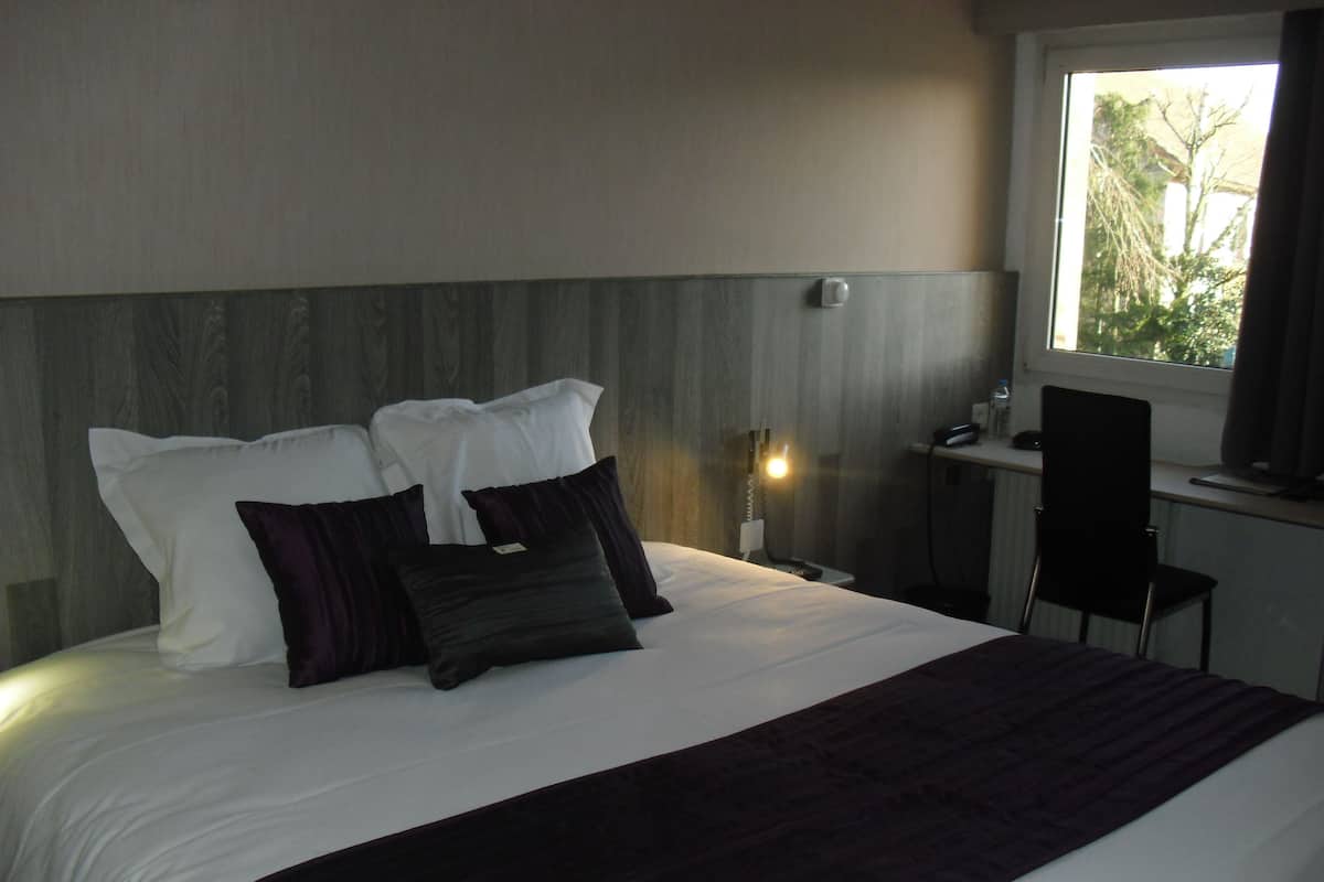 Una habitación de hotel con cama, escritorio y silla.