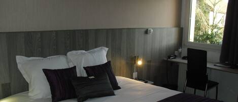 Una habitación de hotel con cama, escritorio y silla.