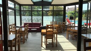 Habitación soleada con techo de vidrio, muebles de madera y vista a una piscina.