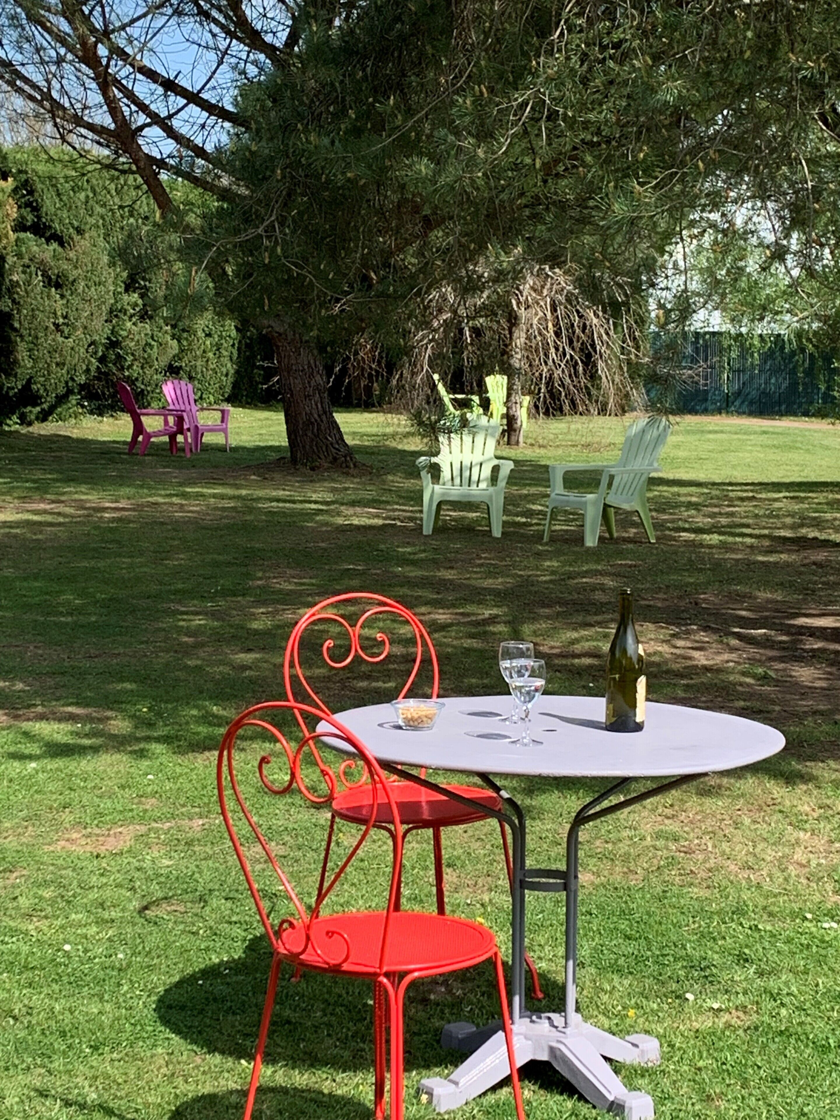 An outdoor seating area with a table and chairs, a bottle of wine, and a bowl of snacks.