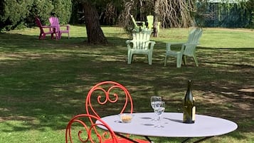 Een terras met een tafel, stoelen, een fles wijn en een schaal met lekkernijen.