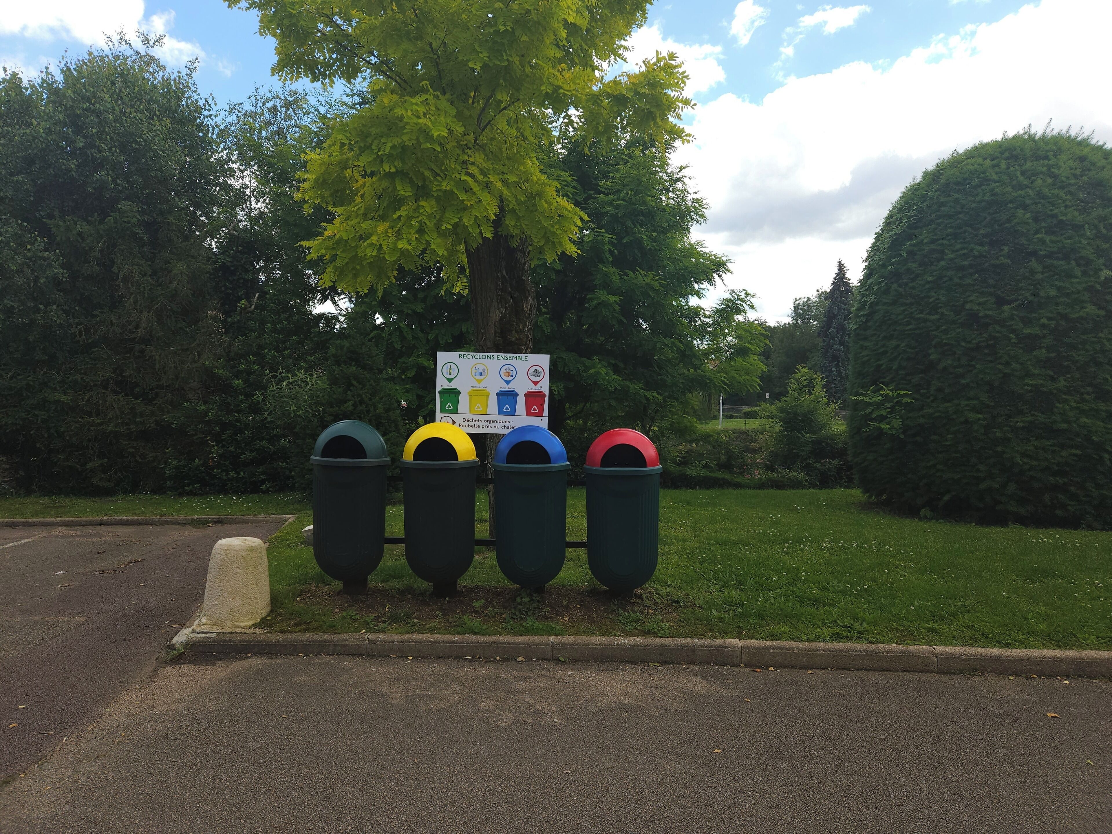 A recycling station with four bins and a signboard.