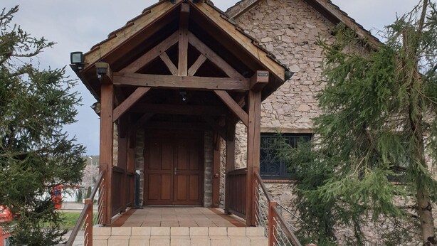 Un edificio con fachada de piedra y estructura de entrada de madera.
