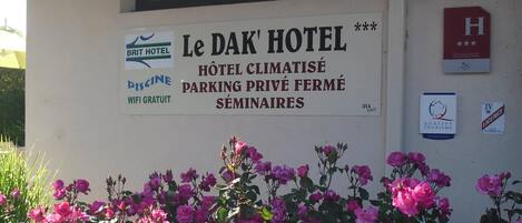 A sign for Le Dak Hotel with amenities like a swimming pool, free WiFi, private parking, and seminars.