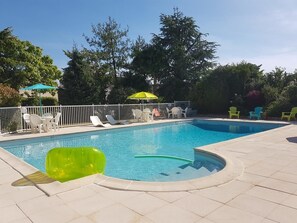 Una piscina al aire libre de temporada, sombrillas, tumbonas