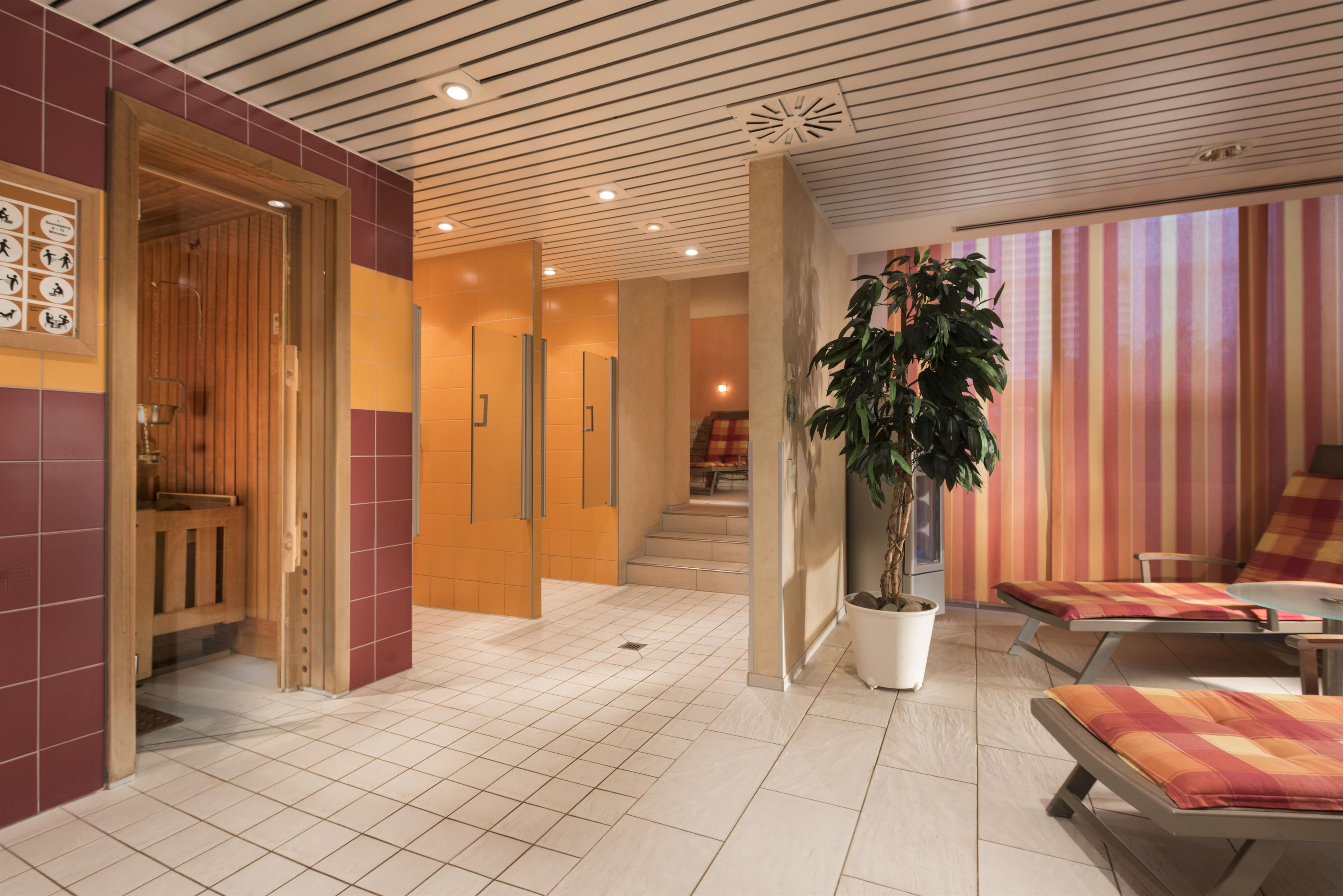 Un moderno vestíbulo de hotel con una recepción, una escalera y una zona de estar con una planta en maceta.