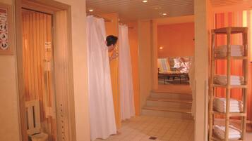 A hotel bathroom with wooden doors, a shower area, and a shelf with towels.