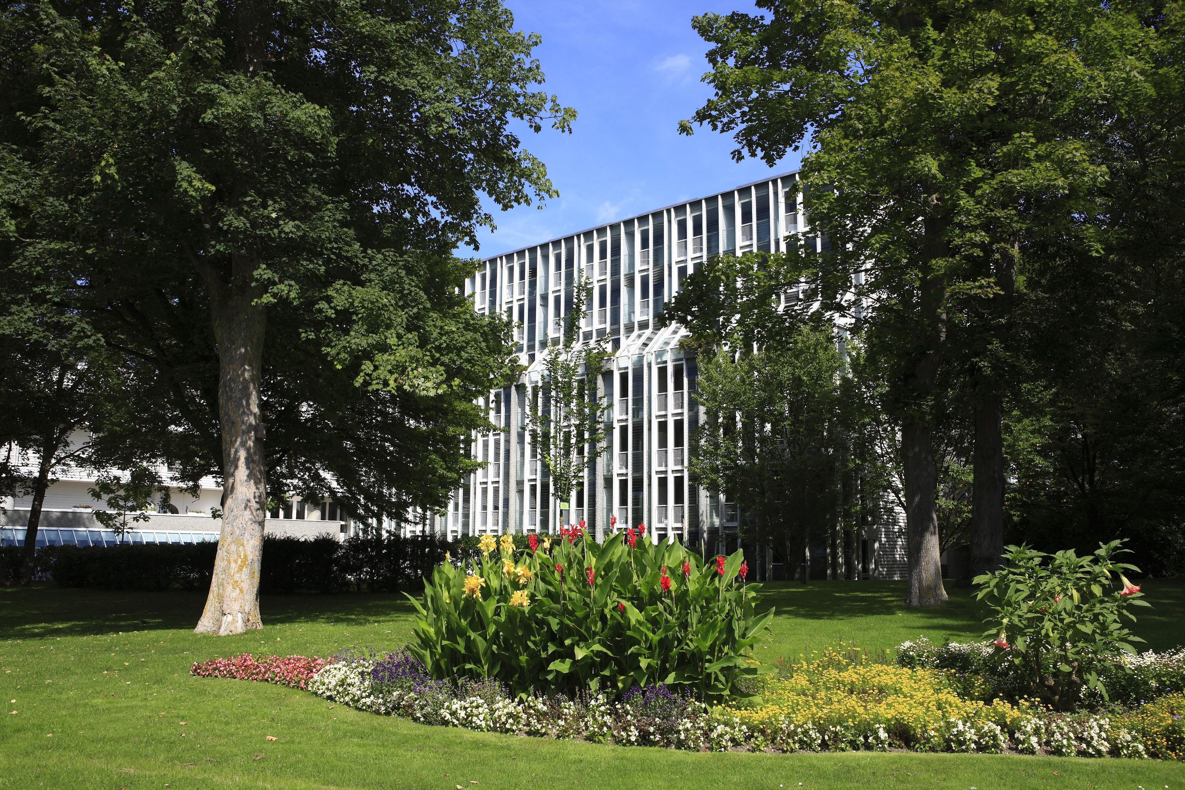 Ein modernes Gebäude mit vertikalen Linien und einem Garten mit verschiedenen Blumen und Bäumen.