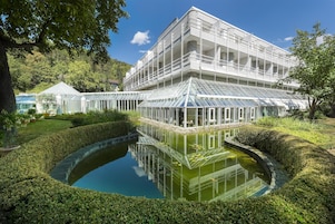 Ein modernes Gebäude mit einem Glashaus und einem Teich, der das Licht reflektiert.