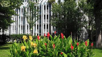 A modern building with a grid-like facade, surrounded by a well-maintained garden with various flowering plants.