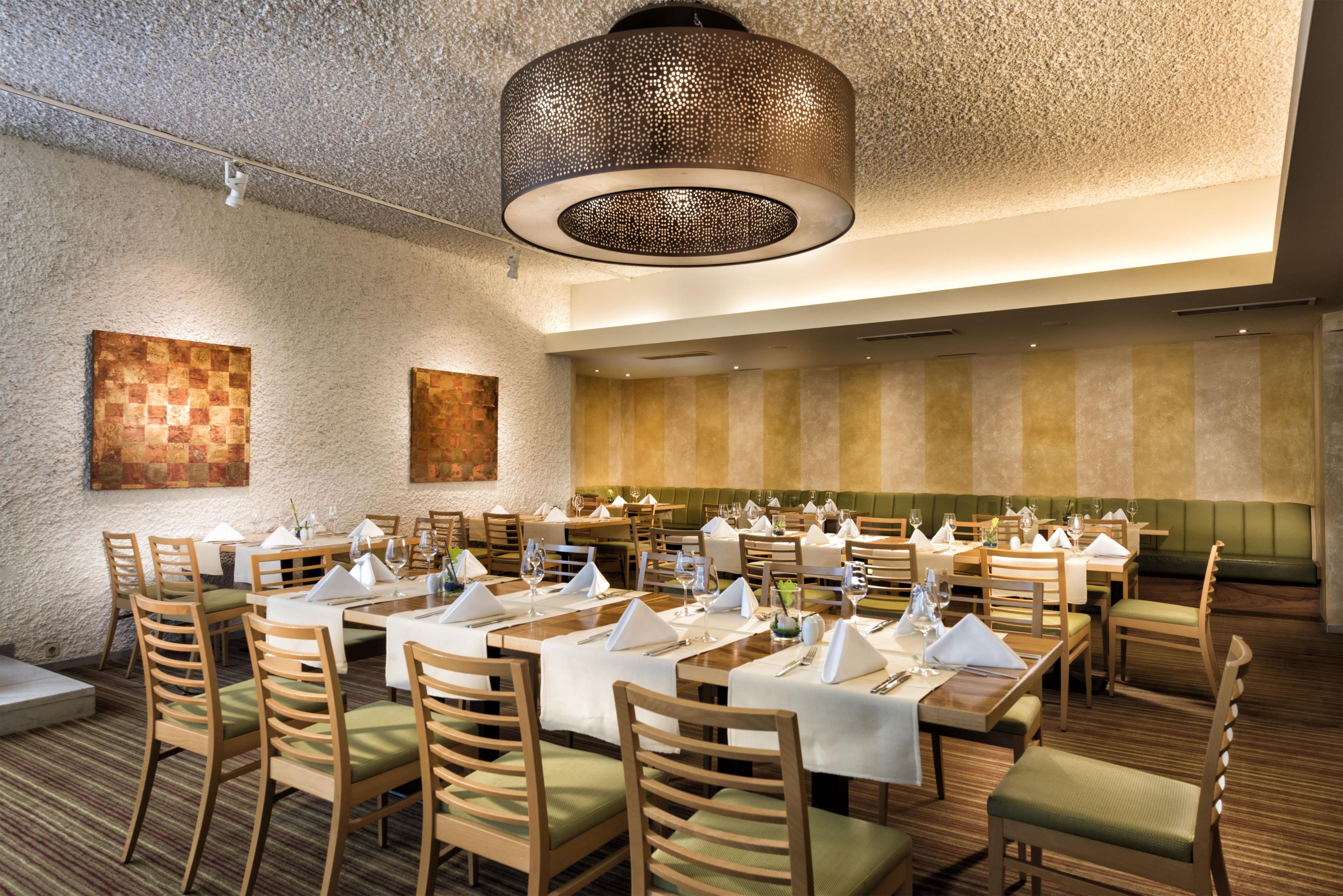 Un restaurante con varias mesas, sillas y una lámpara colgante grande.