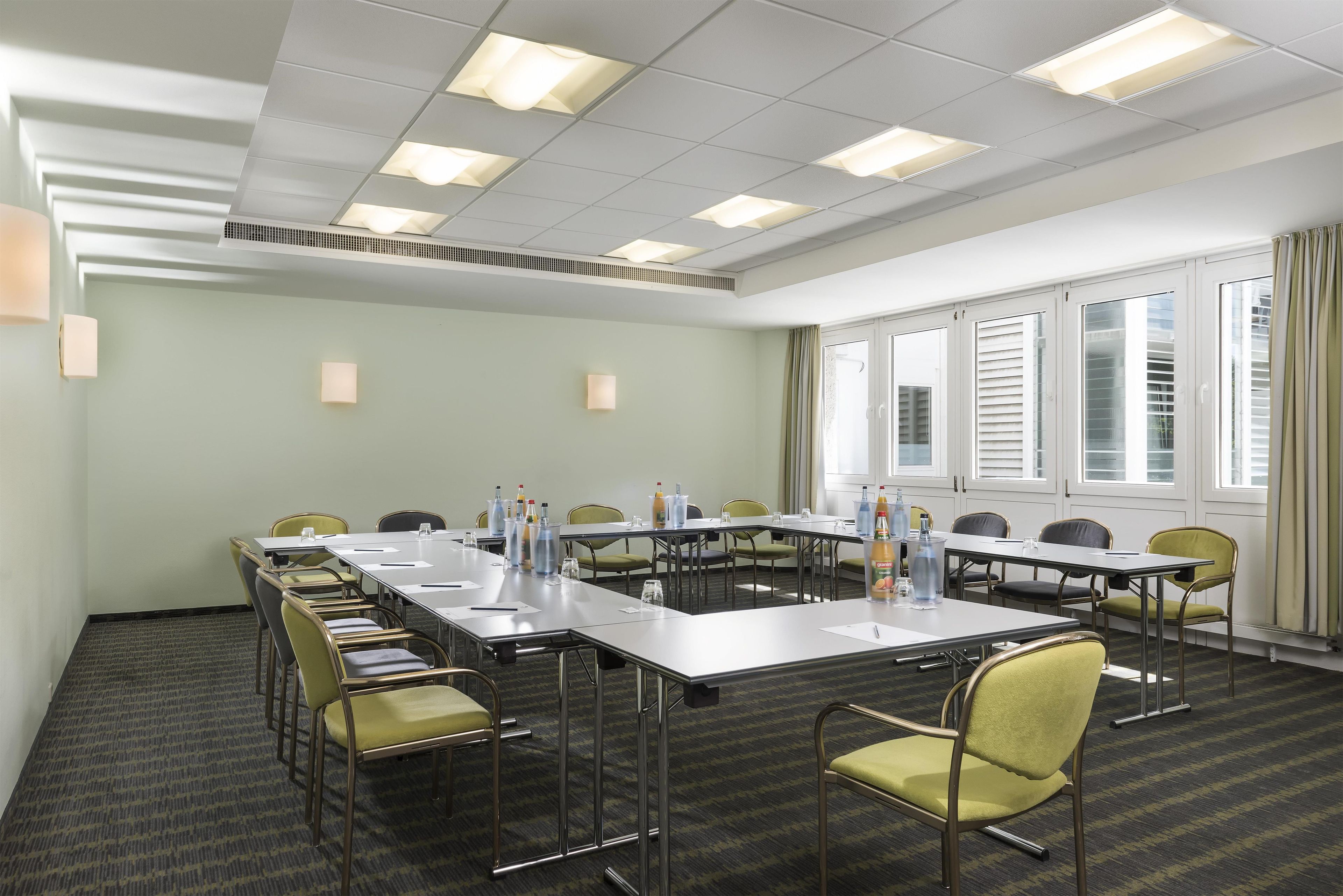 A conference room with a long table, chairs, and a window with blinds.