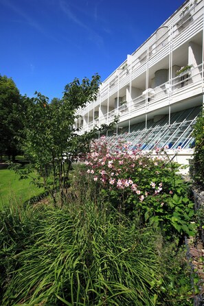 A multi-story hotel with balconies, surrounded by lush greenery and flowering plants.