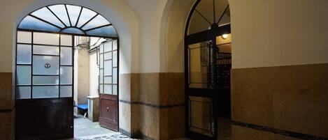 A hallway with tiled flooring, arched doorways, and a tiled wall.
