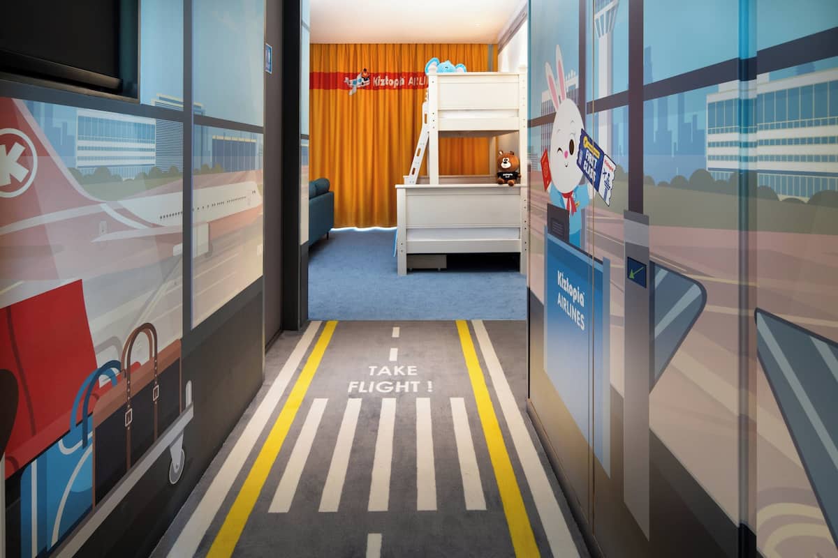 Una habitación infantil con una litera, un tren de juguete y un mural de un aeropuerto.
