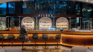 Zona de bar con estantería para vinos, taburetes y mostrador.