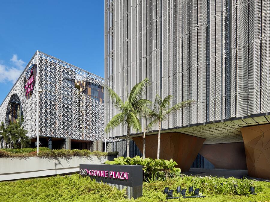 A modern building with a geometric facade and a sign reading "CROWNE PLAZA".