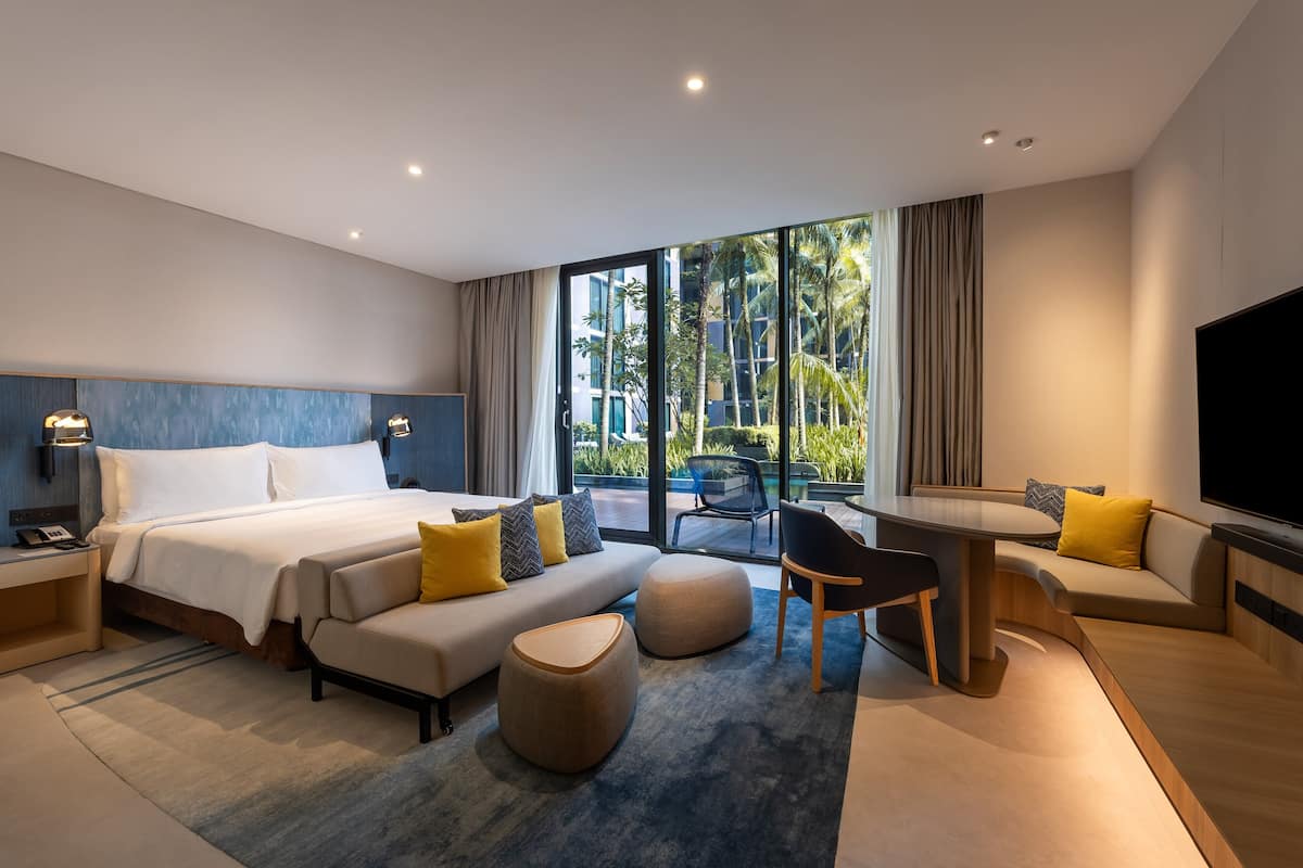 Una habitación de hotel moderna con una cama grande, un sofá, una mesa de comedor y un televisor.
