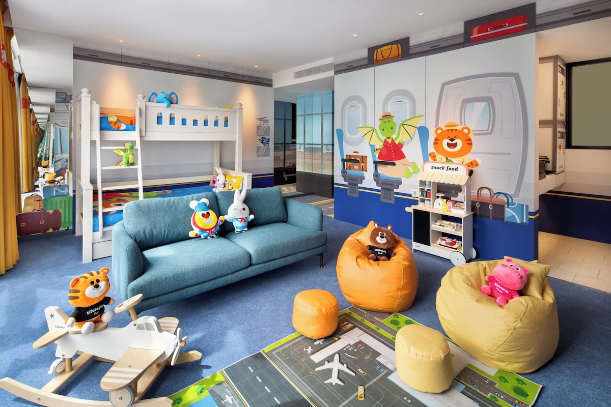 Un cuarto de juegos infantil con literas, un sofá, pufs y varios juguetes.