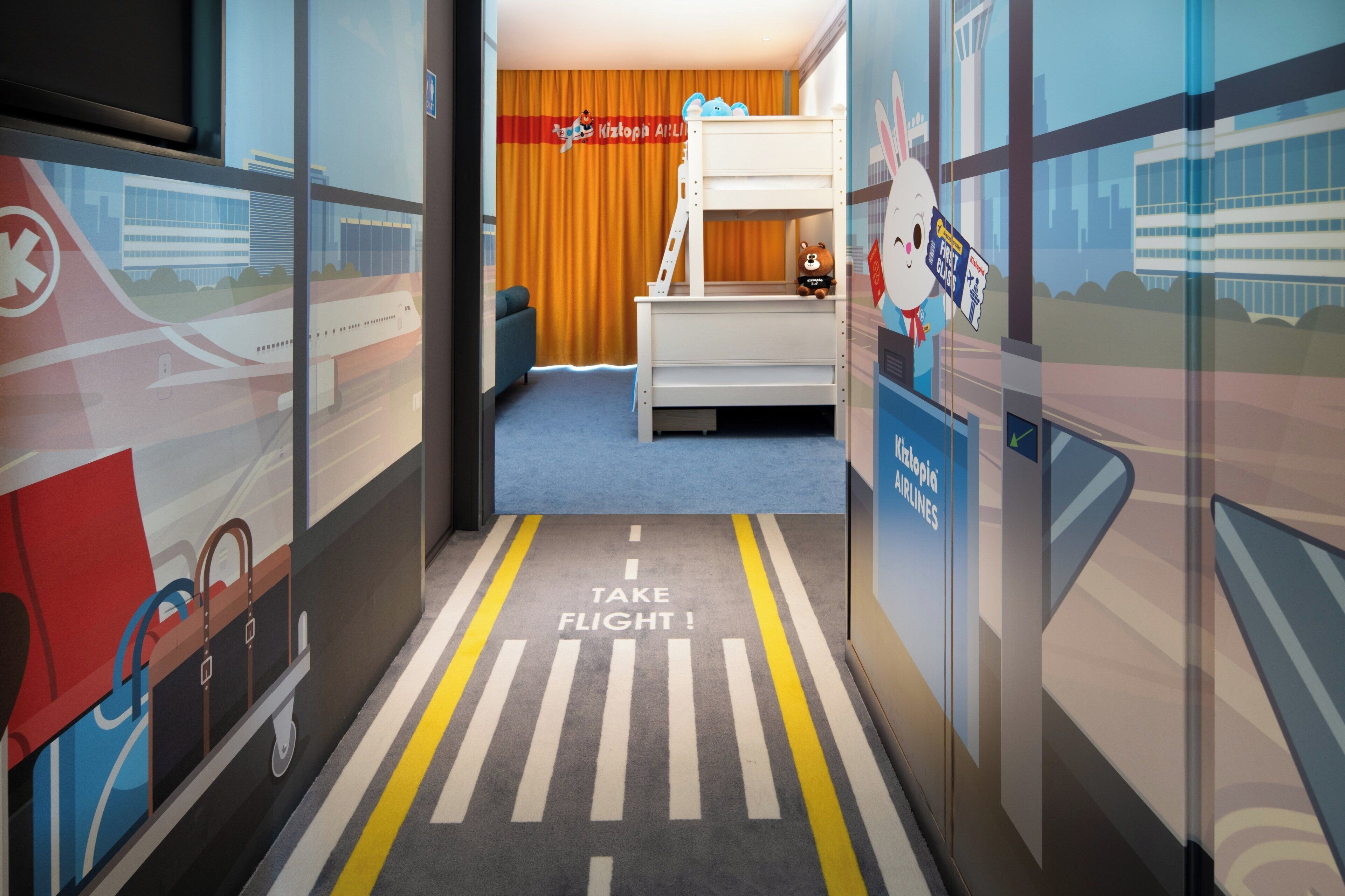 Una habitación infantil con una litera, un tren de juguete y un mural de un aeropuerto.