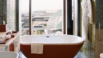 Un baño moderno con una bañera independiente, un ventanal con vistas a la ciudad y un perchero para toallas.