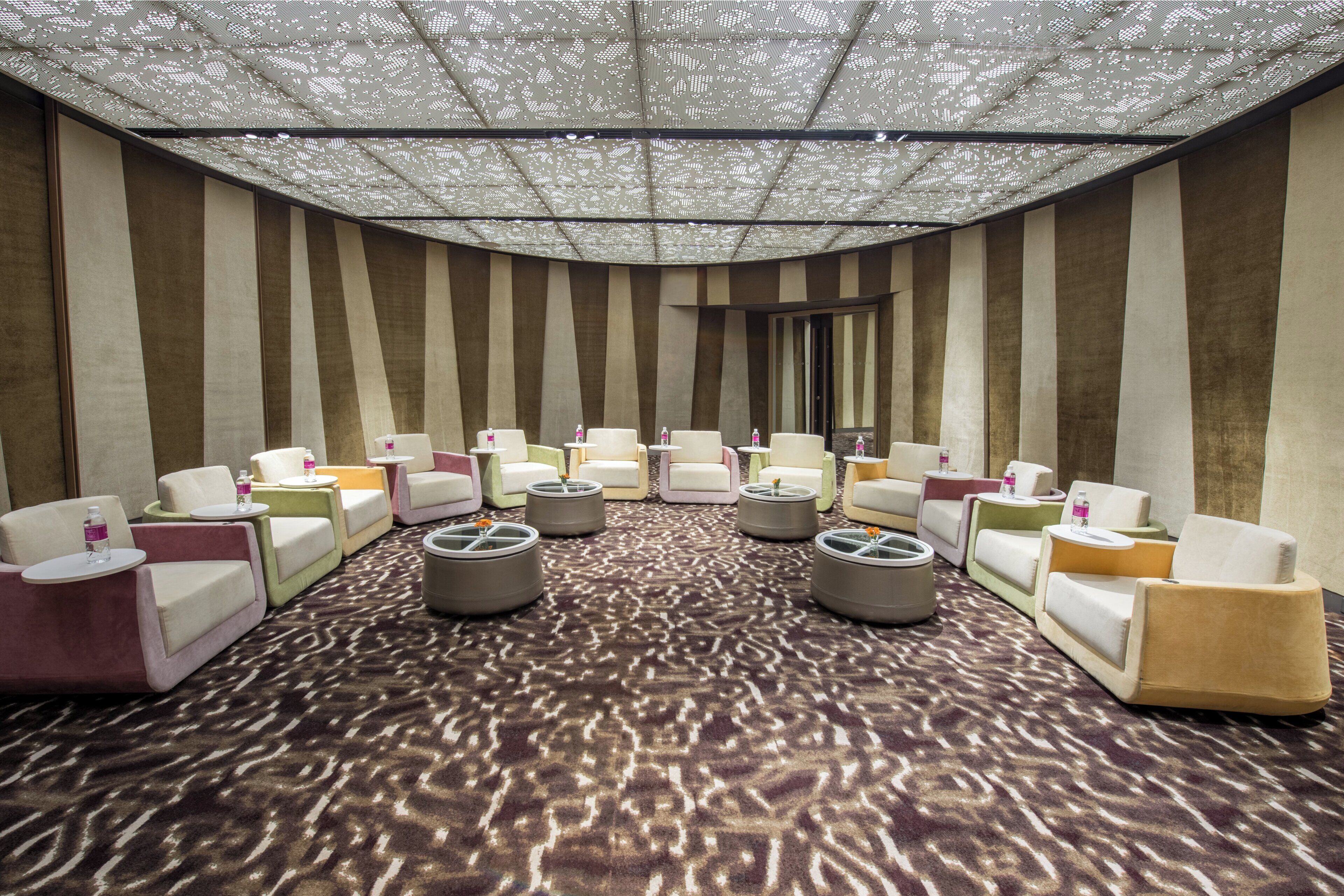 A lounge area with striped walls, multiple seating options, and a patterned carpet.