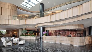 A spacious lobby with a curved reception desk, seating area, and a high ceiling with skylights.