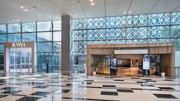 A spacious lobby with a checkered floor, a 'Crown Plaza' entrance, and a 'Jewel' store.