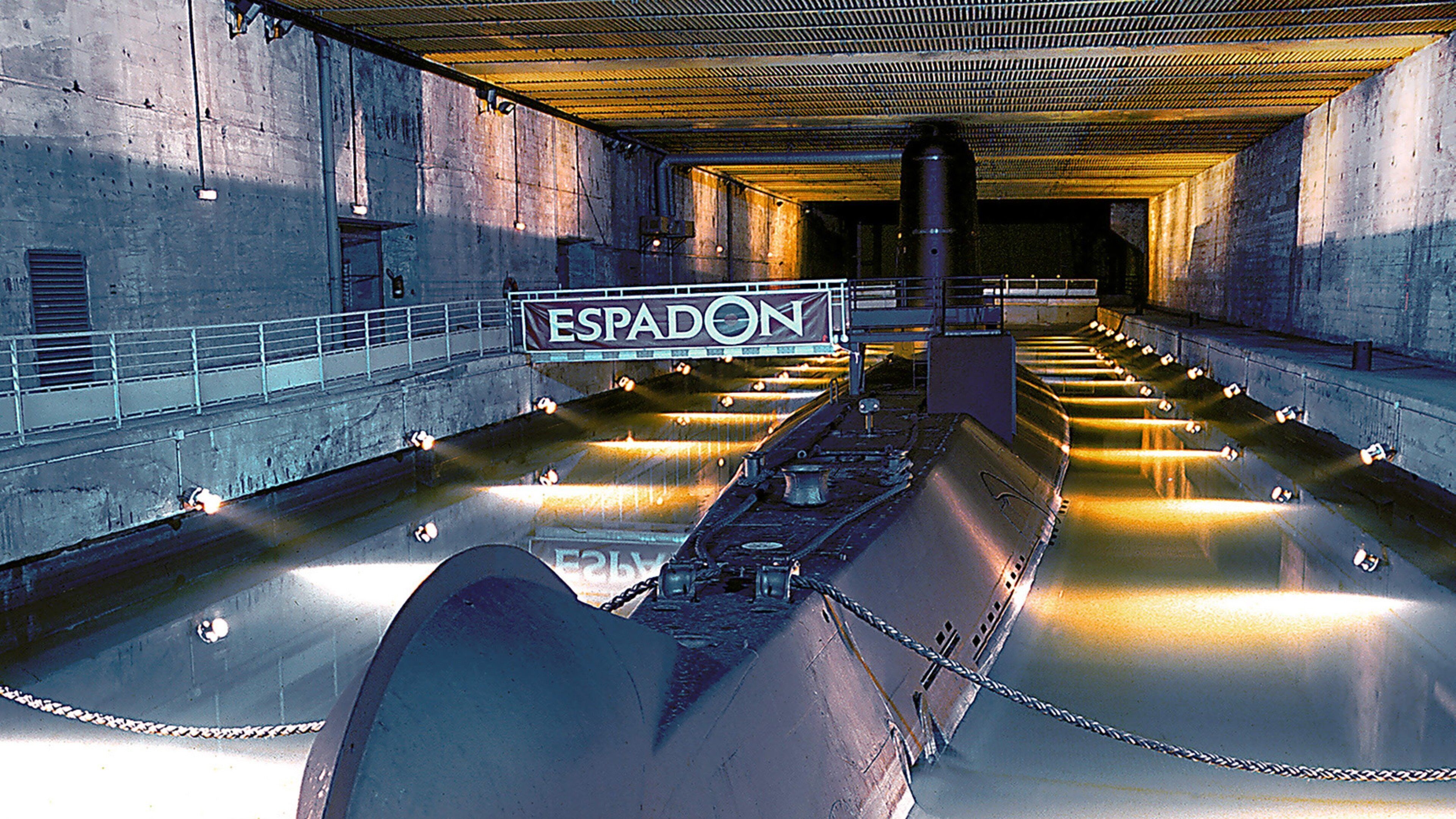 Un amplio espacio industrial con un letrero que dice 'ESPADON' y un canal de agua largo y estrecho.