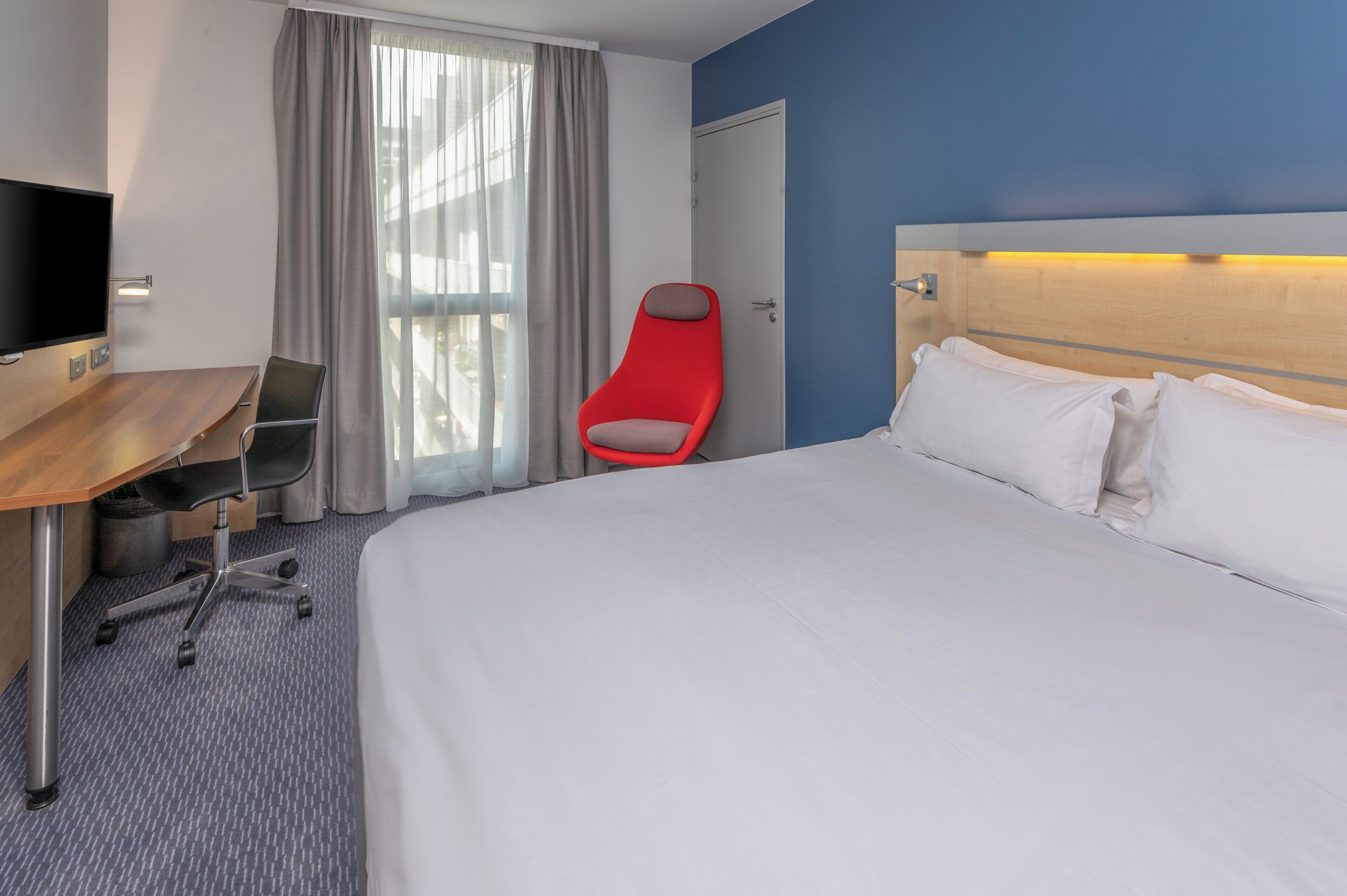 Een hotelkamer met een bed, een bureau, een stoel en een televisie.