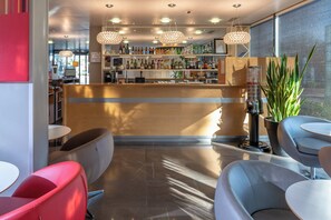 A bar area with a wooden counter, multiple hanging light fixtures, and a variety of bottles. There are seating areas with chairs and tables. - Holiday Inn Express Saint-Nazaire by IHG (Saint-Nazaire)