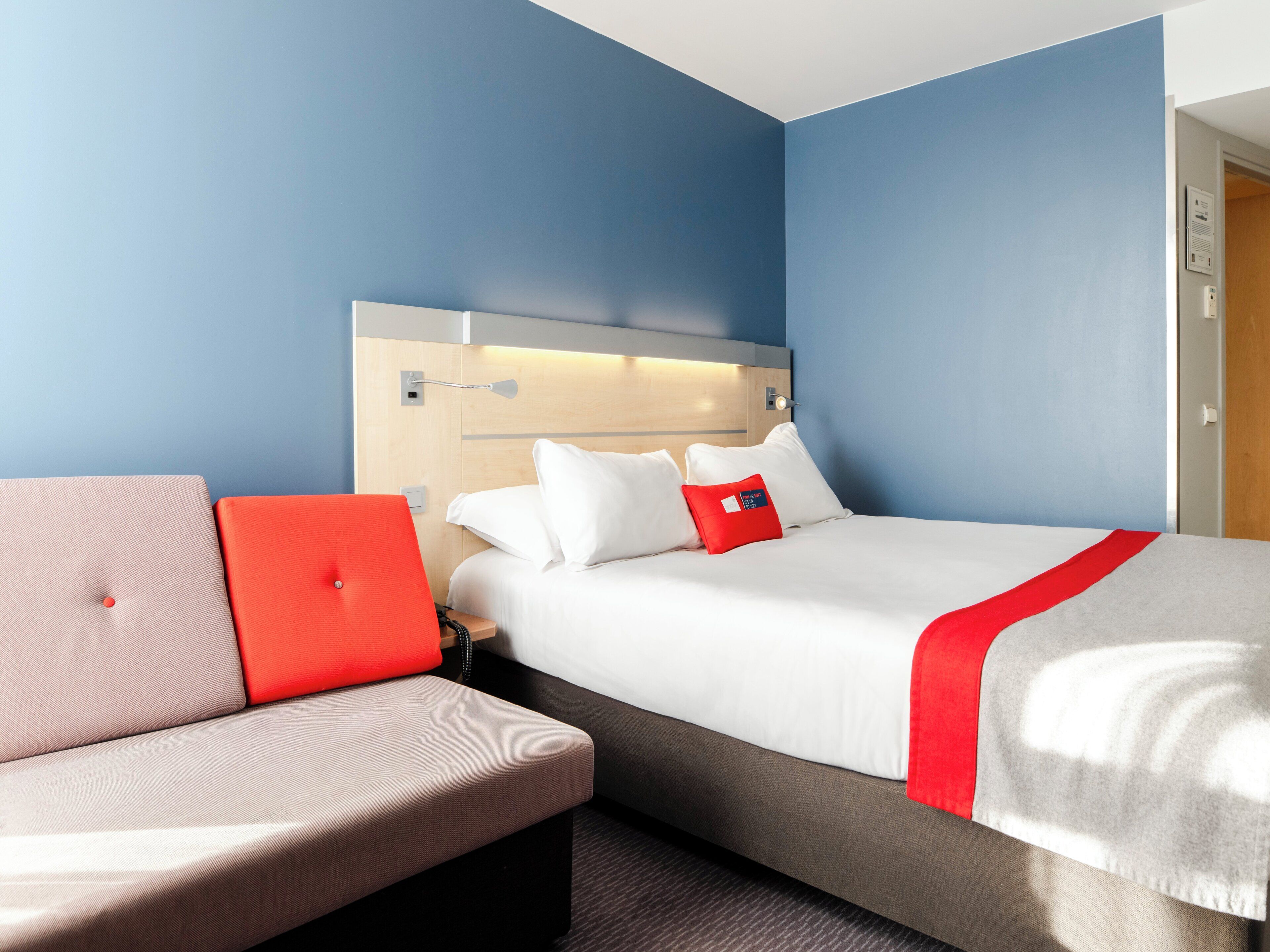 A hotel room with a bed, a sofa, and a nightstand.