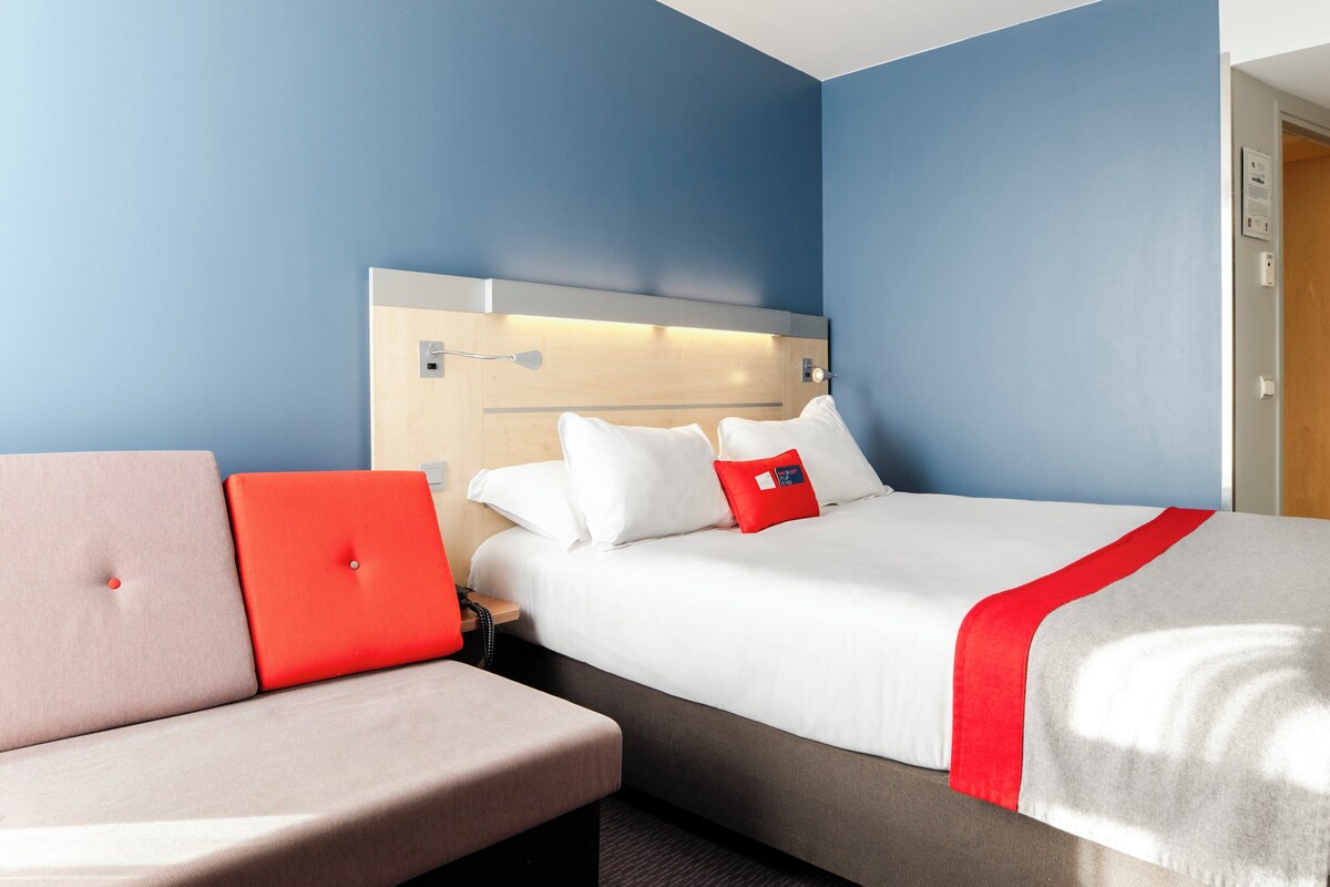 A hotel room with a bed, a sofa, and a nightstand.