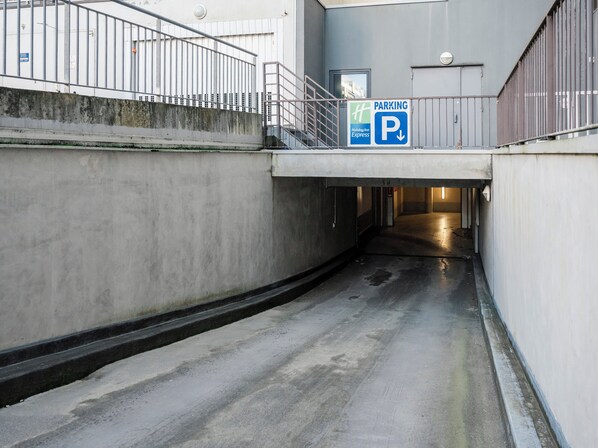 Señalización de estacionamiento para Holiday Inn Express, un camino pavimentado y una baranda de metal.